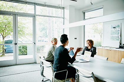 Businesswoman presenting project ideas to colleagues at conference table in office