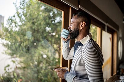 man drinking coffee looking out window